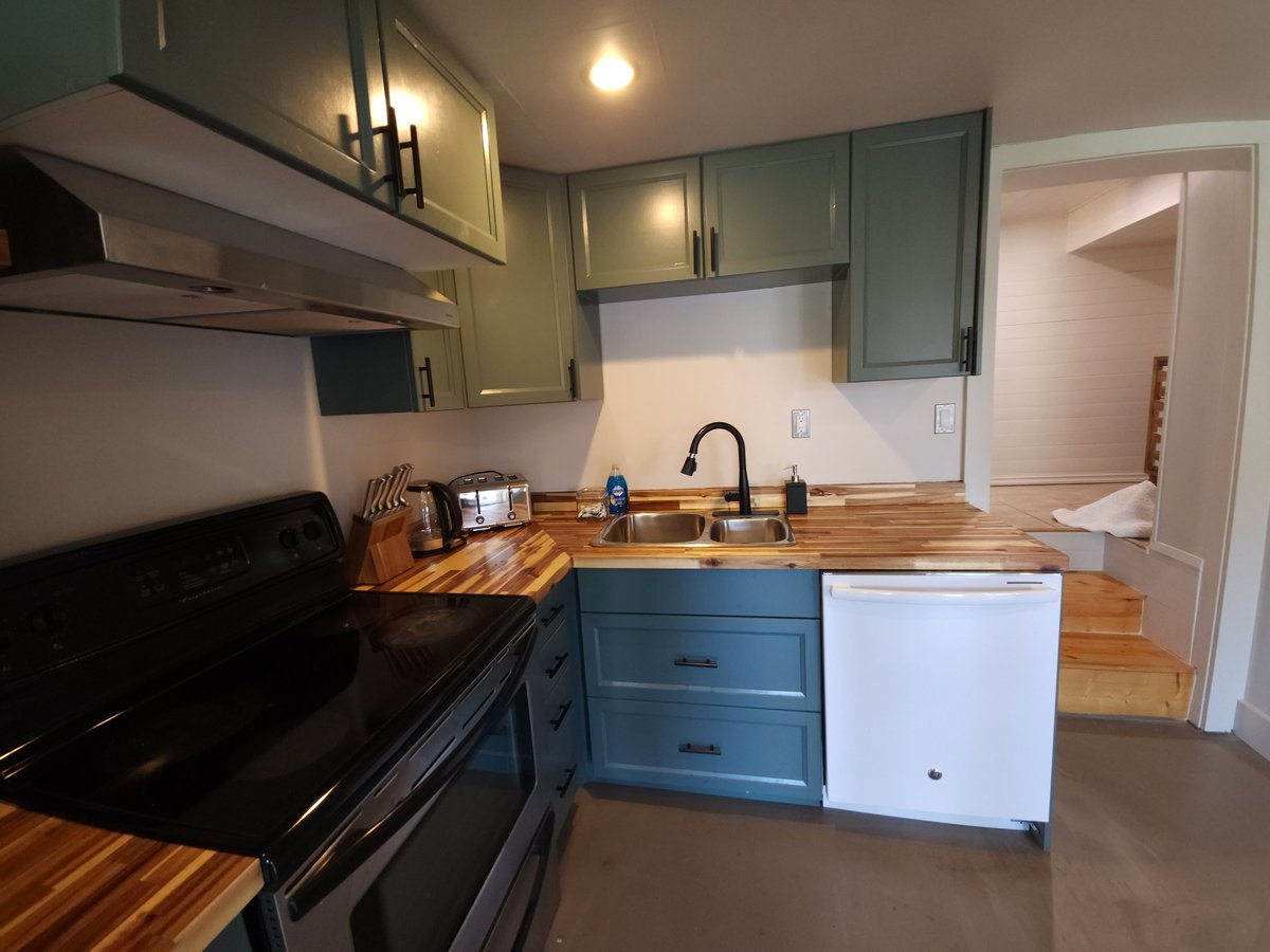 Modern fully equipped kitchen with wood countertops, stainless steel appliances, and island seating